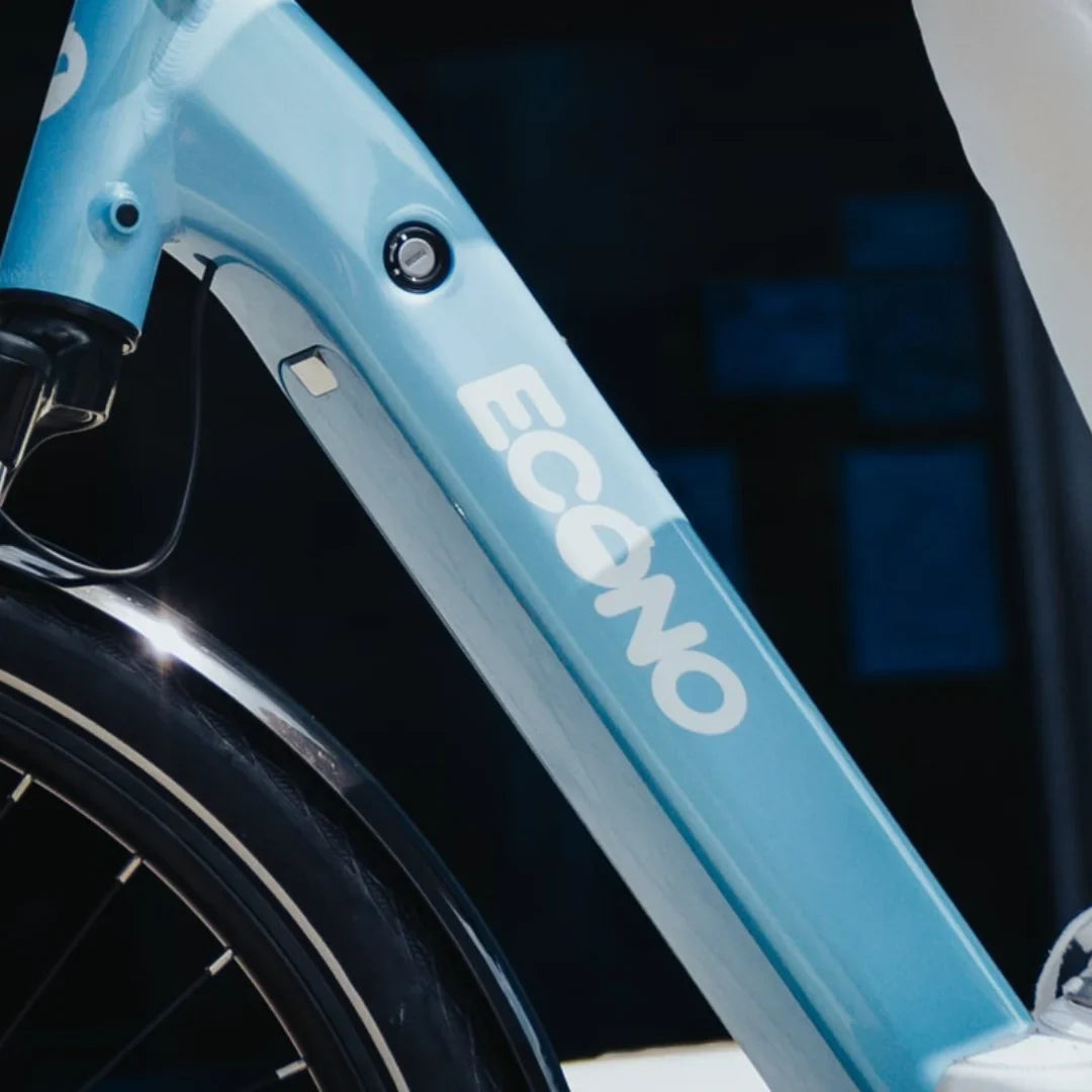 The product is an Electric Bike, brand Econo, model Mare City EEC4LK. The image shows the approximate structure of the bike in light blue, with a prominent Econo logo. The detailed frame finish and battery charging port are also visible. The bike also features wide tires, suggesting a comfortable ride on urban surfaces.