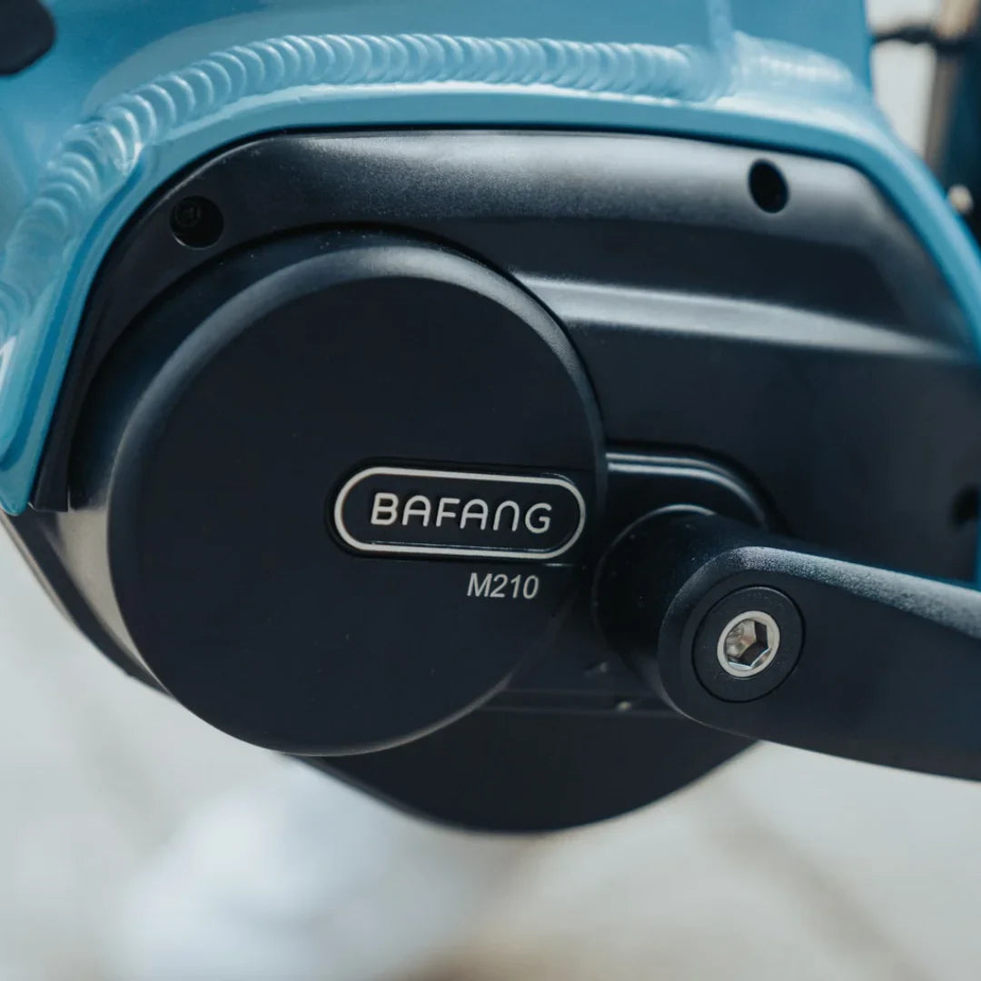 The product is an Electric bike, model Econo Mare City EEC4LK. The image shows a part of the motor, manufactured by the Bafang brand, model M210. The blue frame structure of the bike and a part of the drive system are also visible.