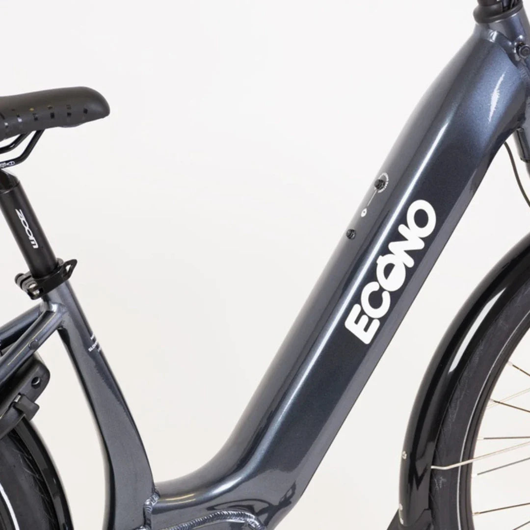 The image shows an Electric bike from the Econo brand, model Mare City. Part of the bike's frame is visible, featuring a modern design in dark grey. The Econo brand logo is clearly visible on the frame, along with buttons for controlling the electric system. The bike is designed for city riding, making it suitable for daily use in an urban environment.