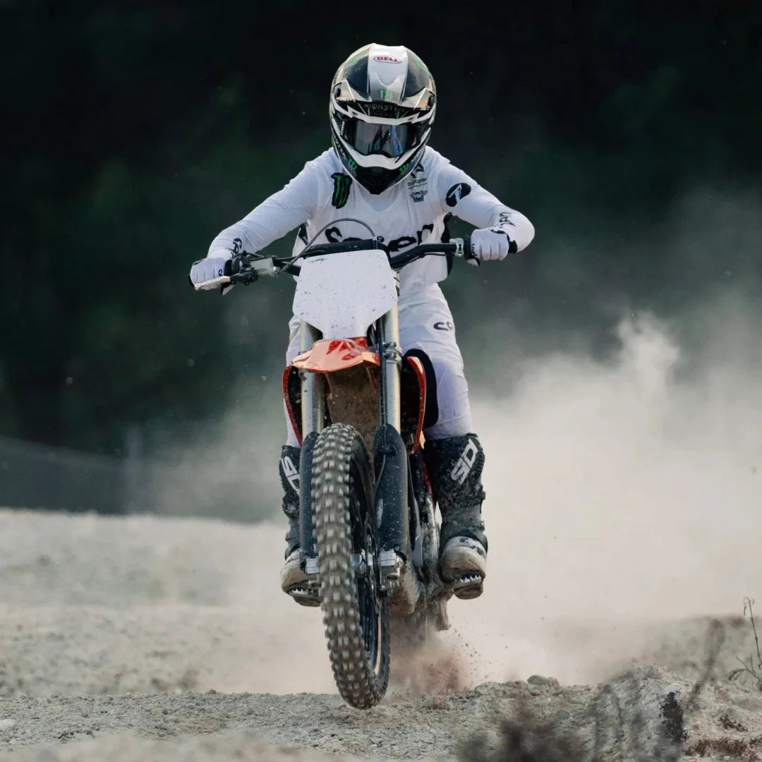 A rider on a Stark Varg electric motocross bike is kicking up dust on a gravel track.
