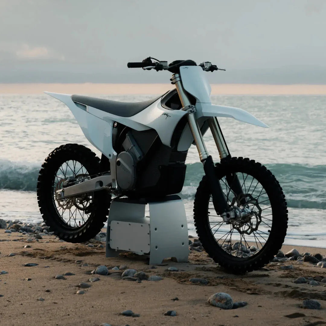 Electric Motocross Motorcycle Stark Varg parked on a beach with waves in the background.