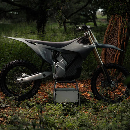 Electric Motocross Motorcycle Stark Varg parked in a lush, green forest environment.