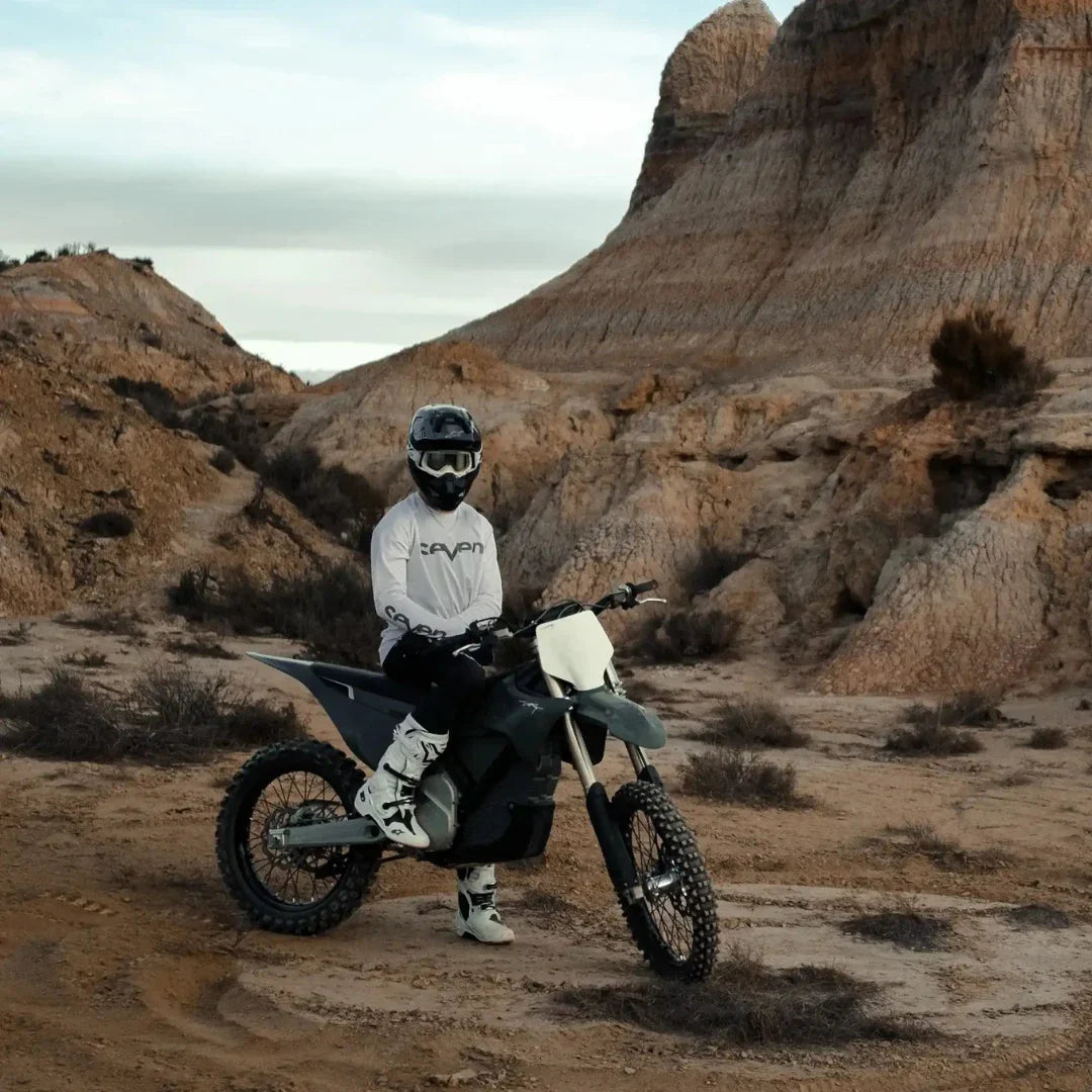 A rider on a Stark Varg electric motocross bike in rugged, rocky terrain.