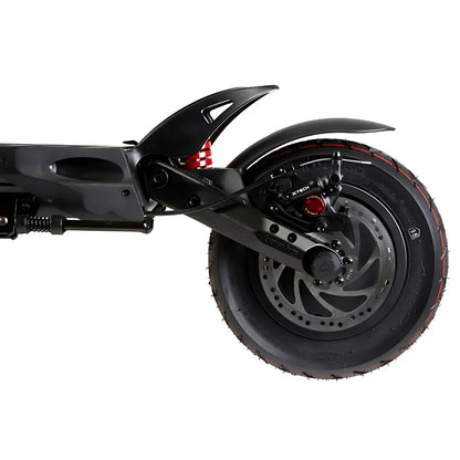 The product in the image is an Electric Scooter, model Kaabo Mantis 10 Plus. The image shows the rear part of the scooter, including the rear wheel, suspension, and brakes. The wheel has a wide tire with a pronounced tread, indicating good grip, while the suspension is designed for a comfortable ride on various surfaces.