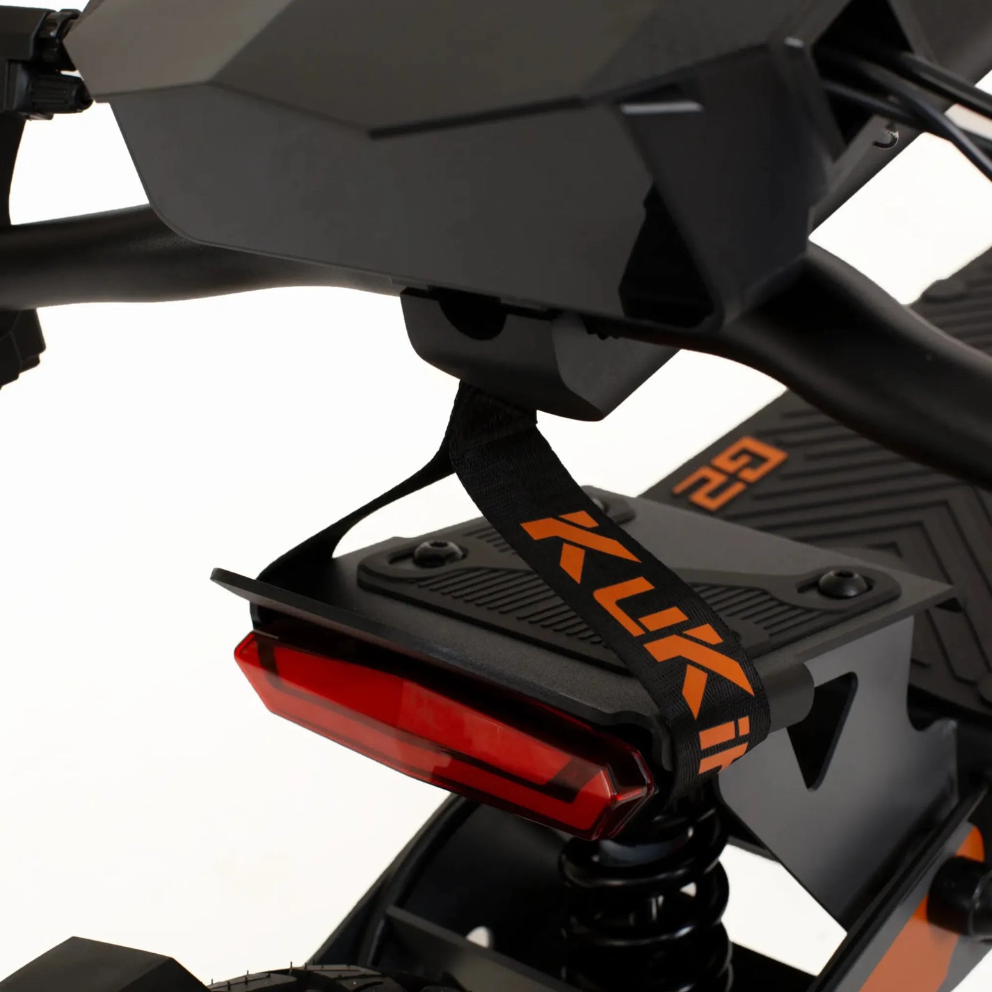 The product in the image is an Electric Scooter, model KuKirin G2. The scooter's red rear light is visible, as is part of the deck, which has a textured surface for better grip. There is also a strap with the KuKirin brand name on the scooter, indicating its identity. The overall design is modern and robust, suggesting the product's quality and functionality.