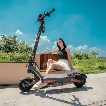 The image shows an Electric Scooter KuKirin G2. The product features a robust design and wide tires, suggesting good stability and riding comfort. A clear blue sky in the background creates a pleasant atmosphere, while a person on the scooter casually leans against a fence.