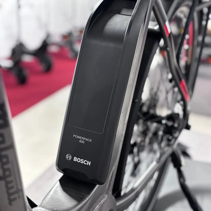 The product in the image is a Malaguti electric bike, model Bolonina. The image shows a Bosch Powerpack 400 battery mounted on the bike's frame. The bike's features suggest a modern design and technology, which is typical for electric bikes. Other bikes are also visible in the background, indicating the environment where the product is displayed.