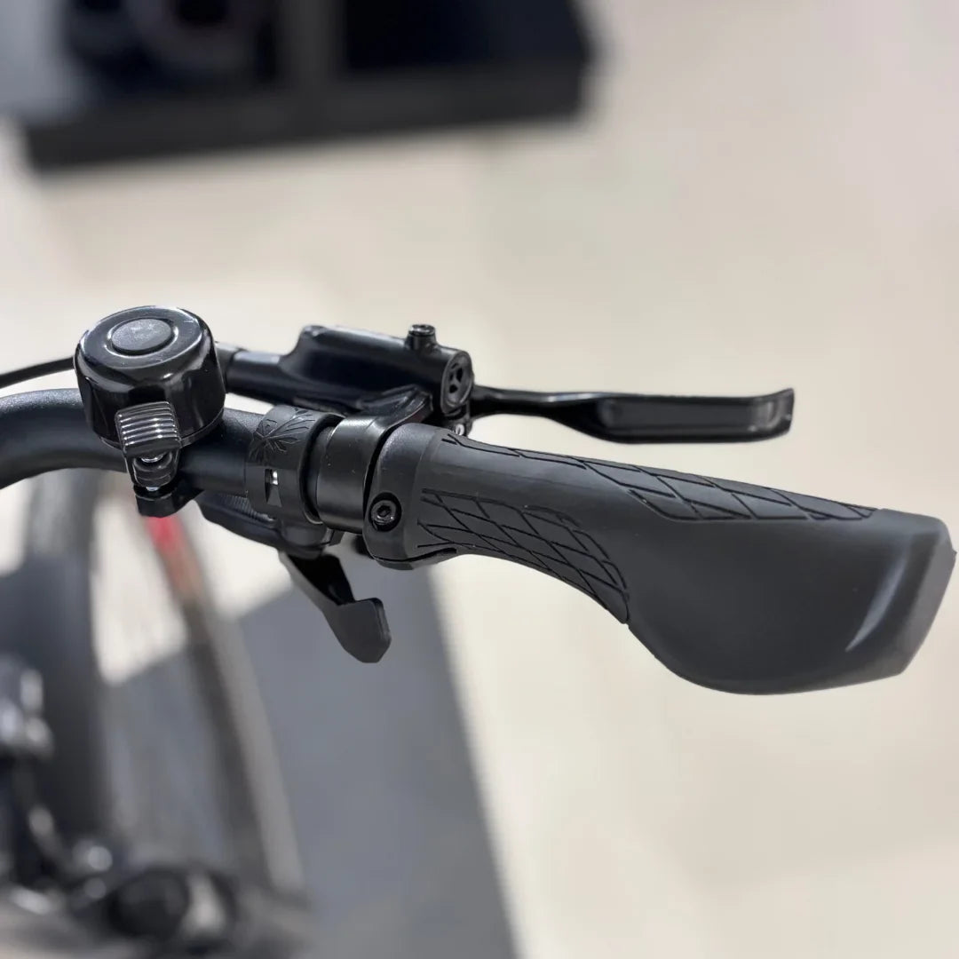 The product is an Electric bike of the brand Malaguti, model Bolonina. The image shows a part of the handlebars, which includes the brake lever, grip, and bell. The grips are designed for comfortable handling, allowing for better control while riding.