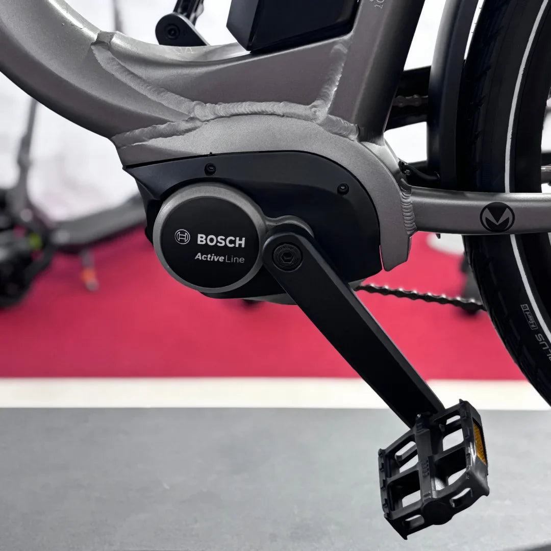 The image displays an electric bike from the Malaguti brand, model Bolonina. The Bosch Active Line motor unit is visible on the lower part of the frame, alongside the pedal. The bike features a modern design and robust construction, indicating quality and performance. The background is blurred, which emphasizes the product.