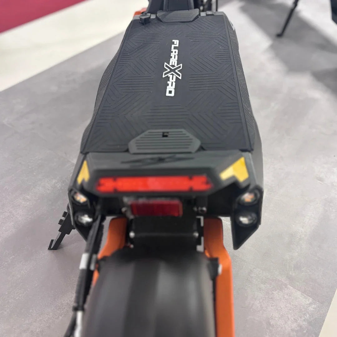 Izdelek na sliki je električni skiro, model MS Energy Flare X Pro. Na sliki je vidna zadnja stran skiroja, kjer so označeni logotip in svetlobni elementi. Skuter ima robustno zasnovo z gumijastim oprijemom na platformi ter značilno barvno kombinacijo, ki vključuje črno in oranžno.