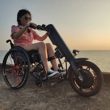 The product is an electric attachment for a wheelchair, model Mijo MT01. The image shows a person using this attachment, which allows for easy movement. The attachment is designed to improve the mobility and comfort of wheelchair users, as is evident from its construction and design. The background shows a calm body of water at sunset.