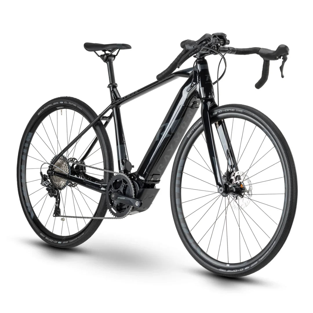 The product shown is an electric bike, brand Raymon, model GravelRay E-7.0. The bike has a sporty design with narrow wheels, making it suitable for gravel and road riding. Hydraulic disc brakes and an electric motor are also visible, indicating its performance and comfort during rides. The color combination is elegant, predominantly black with lighter details.