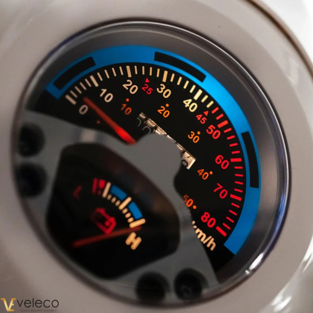 The product in the image is an Electric motorcycle from the brand Veleco, model Cristal. The image shows a speedometer displaying various speed and battery level values. The meter has color indicators, allowing for easy data reading while riding.