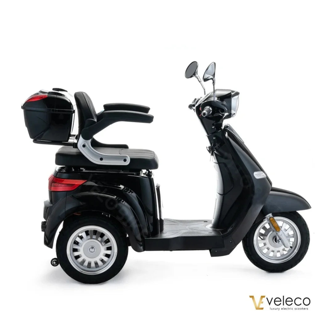 The product is an Electric motorcycle, brand Veleco, model Cristal. The image shows the scooter in black, featuring a comfortable seating area and a spacious trunk at the back. It is equipped with two mirrors and has wide wheels, ensuring stability during the ride.