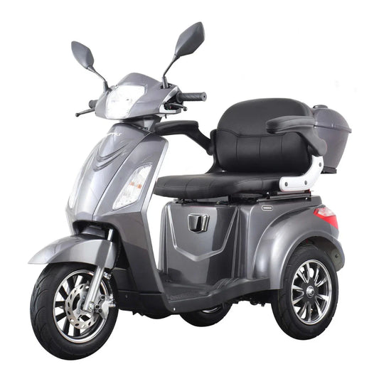 The product is an Electric mobility scooter with three wheels, model Vigorous Vista 1. The image shows the scooter in silver, equipped with a comfortable seat and backrest, and additional storage space. It also features front lights and mirrors, indicating its suitability for urban use.