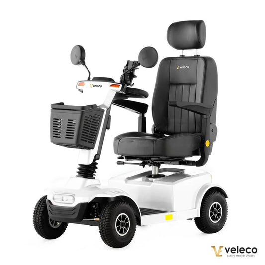 Izdelek na sliki je električni mobilni voziček, model Veleco Jumpy. Voziček je zasnovan za udobno in enostavno premikanje, opremljen z udobnim sedežem in naslonjalom za glavo. Ima tudi ročaje za upravljanje, ogledala ter košarico za shranjevanje. Kolesa so robustna, kar omogoča stabilno vožnjo po različnih površinah.